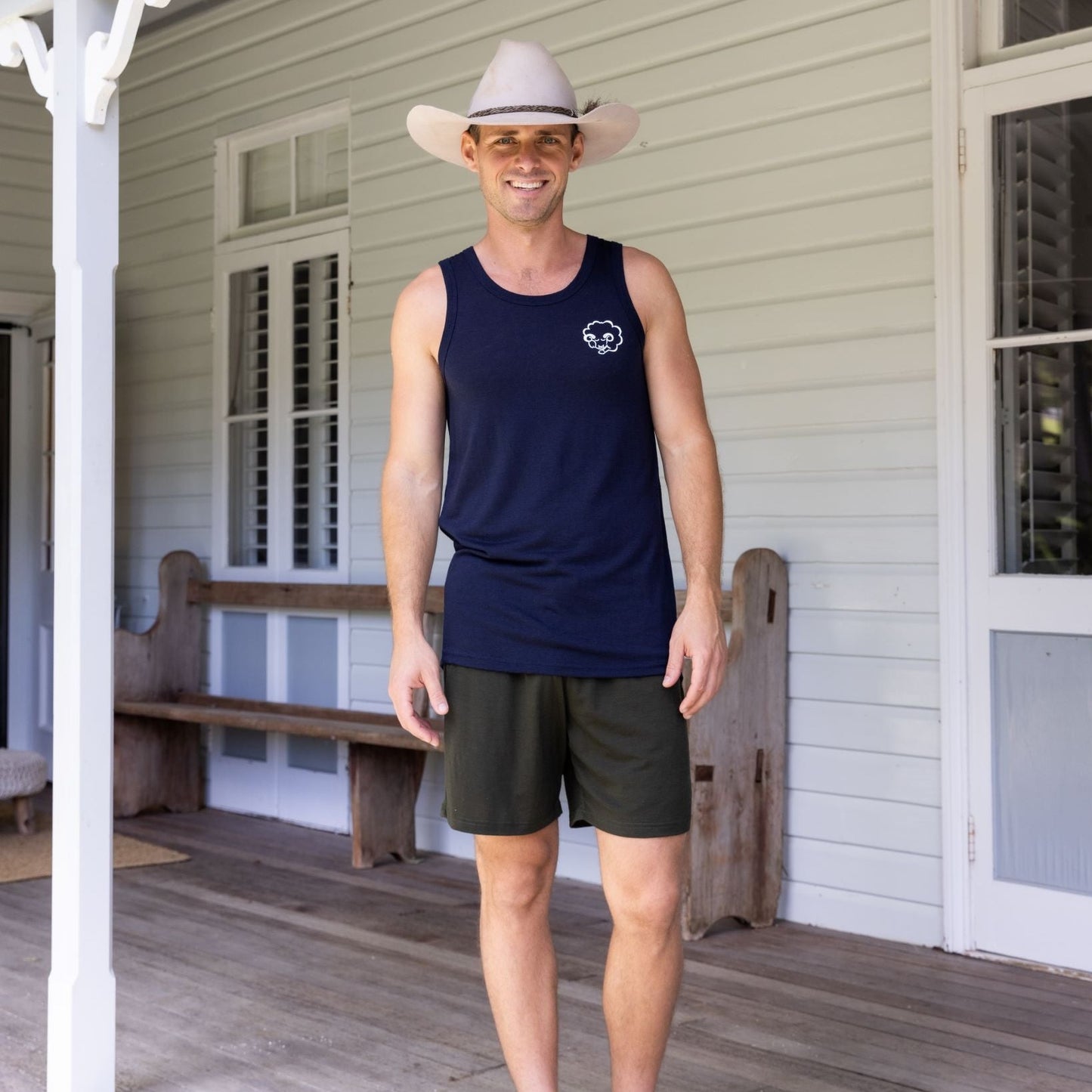 man in hat on verandah wearing Merino shorts and singlet