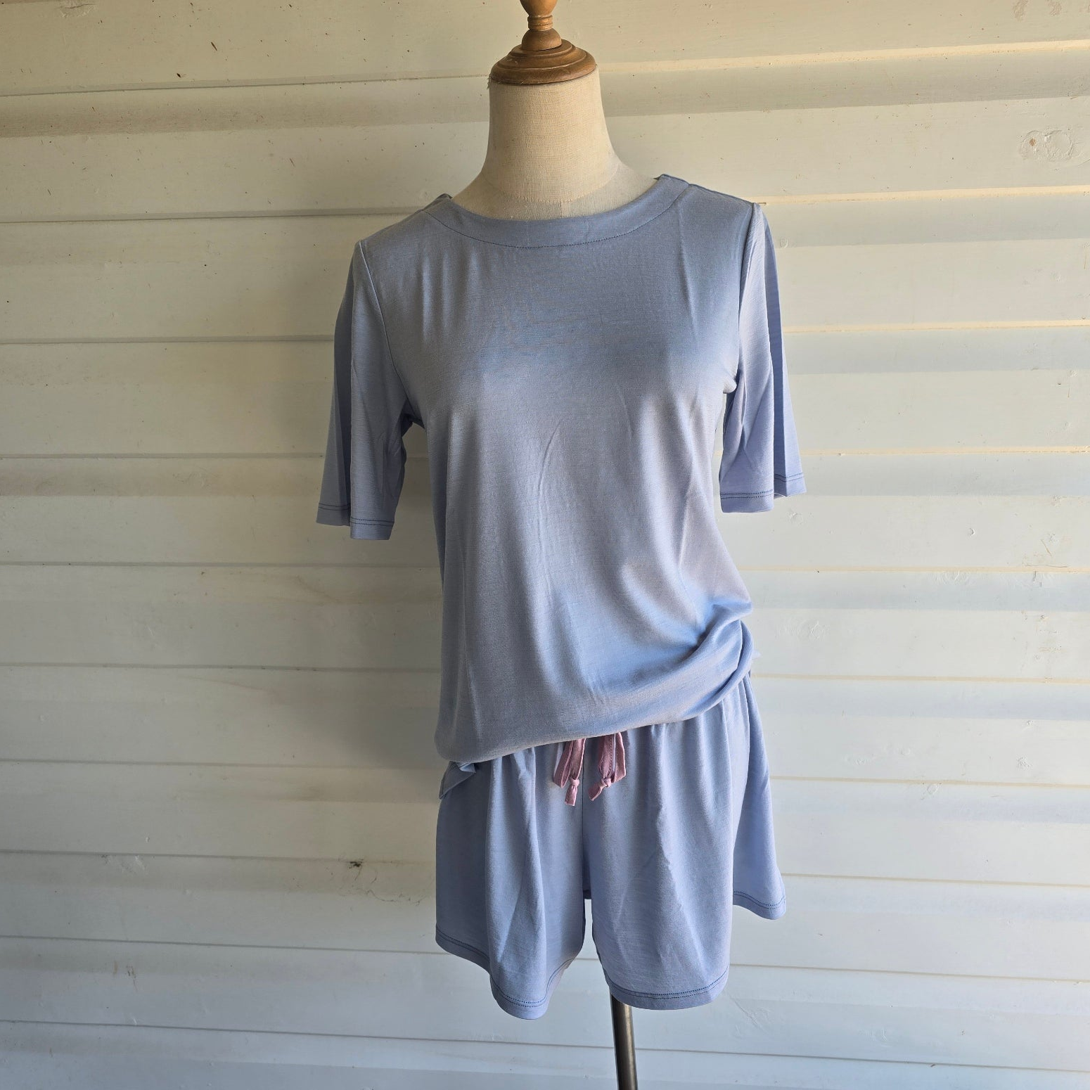Light blue pajama set on a mannequin against a white wooden panel background